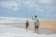 © Sergey Novikov - Kids enjoy beach fun run with a toy plane and the ocean waves
