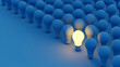© emwe studio - Single glowing yellow light bulb standing out from blue bulbs symbolizing unique idea and business leadership