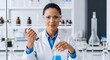 © khan - Woman scientist in lab coat and goggles uses pipette with blue liquid in flask laboratory research