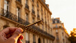 © tilialucida - Hand holding ornate vintage key against Parisian apartment facade at sunset