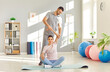 © Studio Romantic - Caregiver or physical therapist helping woman in doing exercises sitting on mat in rehabilitation center. Man physiotherapist helping girl in rehab. Physiotherapy and osteopathic medicine concept.
