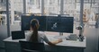 © Framestock - Female Engineer on Headset, Managing 3D Robot Automation Model and Performance Metrics on Monitors. Control Room Overlooks Industry 4.0 Factory Floor. Smart Manufacturing and Robotics Management.