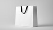© VictorCanalesStudio - White paper bag with a black ribbon handle standing against a light grey background