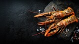 Fresh cooked lobsters on dark slate with sea salt and peppercorns.