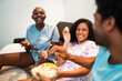 © Nexa - Happy diverse friends laughing and eating popcorn during a movie night at home.