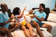 © Nexa - Happy multi-ethnic family playing and throwing popcorn while sitting on the couch at home.