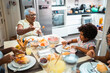 © Nexa - Senior African American woman and her young granddaughter enjoying a healthy breakfast together in a bright kitchen with family members.