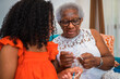 © Nexa - Senior African American grandmother teaching her young granddaughter how to crochet at home, sharing a special bonding moment together.