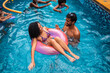 © Nexa - Happy young couple playing in a swimming pool with inflatable rings during a summer vacation.