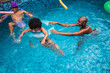 © Nexa - Happy multi-generational Black family enjoying a sunny day in a swimming pool, with a young girl in an inflatable ring and her mother and grandfather playing together.