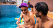 © Nexa - Two male friends enjoying refreshing cocktails by a swimming pool during a sunny summer vacation.