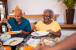 © Nexa - Happy elderly African American mother and her adult son enjoying a healthy lunch together at home.