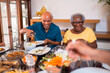 © Nexa - Happy African American family sharing a delicious meal and laughing together at the dining table.
