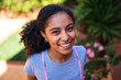 © Nexa - Portrait of a Smiling Young Black Woman with Curly Hair Outdoors in a Garden Setting