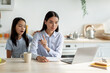 © Prostock-studio - Bored asian girl demanding attention from her busy mother, woman working at home and ignoring her lonely child. Freelancer lady using laptop while sitting in kitchen, copy space