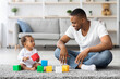 © Prostock-studio - Black Millennial Father And His Adorable Infant Baby Playing With Building Blocks At Home, Young African Dad Having Fun With His Cute Toddler Child While Sitting Together On Floor In Living Room