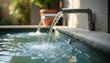 © AlenaSi - Flowing water feature from metal spout into outdoor pool, creating soothing ripples. Modern water feature design highlights clear refreshing stream and calm surface.