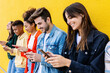 © Xavier Lorenzo - Happy group of young multiracial friends using smart phones together outside over yellow background. Social media and technology lifestyle concept