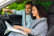 © Prostock-studio - Happy young middle-eastern couple sitting in car with road map, planning their weekend journey, side view. Cheerful pretty brunette lady showing her boyfriend destination to go, travelling together