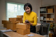 © Wasana - Asian female seller using smartphone to check order details in startup home office