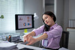 © Wasana - Office worker stretching arms at desk after work on computer