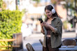 © Apichat - Young woman enjoying music with headphones and smartphone outdoors
