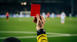 © MUHAMMAD - A referee holds up a red card on a soccer field with players in the background