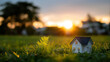 © Kateryna - Small house model on green lawn at sunset eco friendly energy efficient family home concept sustainable residential living environmental housing banner format with generous