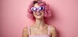 © miss irine - Young woman with pink hair and heart glasses smiles broadly against a solid pink background. She wears a pink top, radiating joy and playful fashion sense.