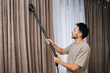 © dikushin - Man professionally steam cleaning curtains in modern home, providing deep drapery maintenance and effective dry cleaning for textile hygiene and fresh living space.
