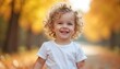 © Vadym - Blonde curly toddler girl smiles happily in autumn park. Child wears white shirt among golden fall leaves. Outdoor portrait shows pure joy and innocence, perfect for seasonal themes.