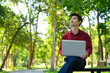 © Prathankarnpap - Happy asian man using a laptop in a park