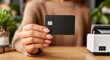 © Yurii Semonov - Close-up woman hand holding black credit card beside white electronic payment terminal