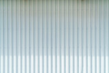 White corrugated metal wall background texture with vertical lines and rivets. Clean industrial surface for construction or architectural backdrop. Frontal view with bright natural light.