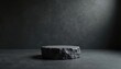 © Maryna - Rough textured dark stone podium for product display against grunge backdrop. Minimalist stage for presentation on concrete floor. Studio shot with dramatic lighting.