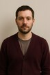 © Татьяна Евдокимова - Man with dark beard and cardigan gazing confidently into camera in a simple studio headshot, neutral background, casual style
