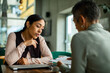 © Geber86 - Adult businesswoman discussing paperwork with mature colleague in office, thoughtful