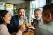 © Geber86 - Adult and mature friends laughing while toasting wine at restaurant