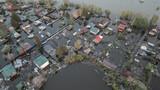 Aerial drone footage of a massive city flood with houses and streets submerged under water. Urban flooding caused by extreme weather and heavy rainfall, showing natural disaster impact on residential 