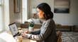 © Ardhia - Woman working from home, focused on laptop in cozy remote work environment