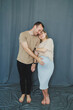 © DSMT - Couple stands together in front of blue backdrop during pregnancy photo session in a studio