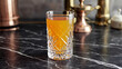 © Kmikhidov - A crystal glass holds gold-tinted citrus juice on a black marble counter, surrounded by blurred kitchen decor during the day