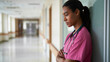 © olgakris - Exhausted nurse leaning against hospital corridor wall showing emotional burnout physical fatigue after long shifts, modern healthcare environment highlighting workforce stress, mental health strain