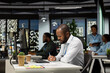 © DC Studio - African american employee writing growth strategy notes on a textbook, working in office at night with insights and financial data. Consultant ensuring operational success and efficiency.