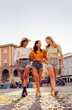 © Xavier Lorenzo - Multiracial young female friends walking in city square. Happy women enjoying a sunny vacation together in an urban setting. Friendship and travel concept.