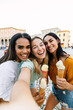© Xavier Lorenzo - Vertical shot of three young diverse women taking selfie during their summer vacation while enjoying an ice cream. Happy female friends celebrating friendship on a sunny day