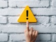 © Jumpei - 注意喚起の黄色い警告マークを指で示して重要なポイントを伝える確認イメージ写真