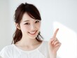 © Jumpei - 指を立ててポイントを伝える明るい表情の若い女性の案内イメージ写真