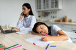 © Prostock-studio - Boredom concept. Busy mom working remotely at home and ignoring her little daughter, kid feeling bored and lonely, drawing on paper. Asian mother and daughter sitting in kitchen