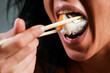 © Volodymyr - Woman eating sexy sushi with chopsticks. Sensual sexy model tasting sushi roll. Sushi in woman mouth. Model eat sashimi. Sensual bite of sushi. Asian food.